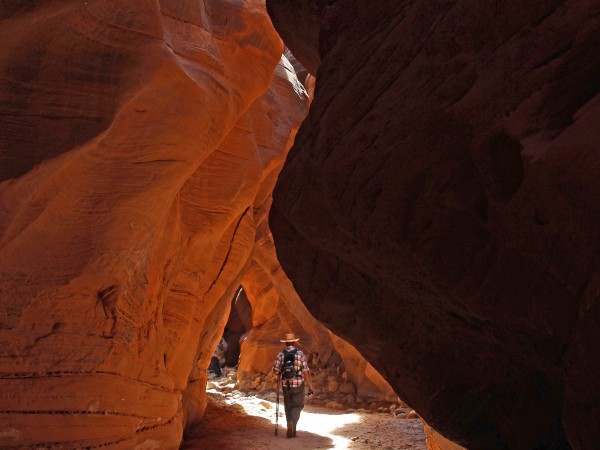 A hiker under a shaft of light, in Buckskin Gulch, in Vermillion Cliffs National Monument, Utah. Accessed from Wire Pass Hiking Trail. Easy Hikes. Grand Canyon Area