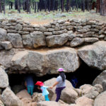 A family standing on the boulders outside the opening of the Lava River Tube, on the Lava River Tube Trail, near Flagstaff, Arizona. Easy Arizona hiking trails. Flagstaff area hiking trails. Arizona family friendly hiking trails. Copyright azutopia. No use without permission.