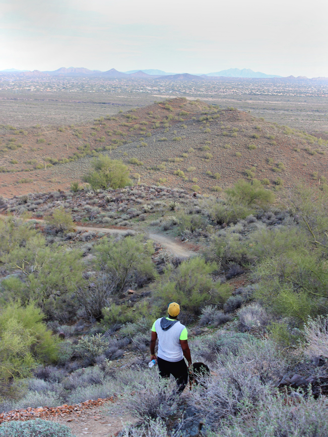 A landscape view of a hiker and his dog; on the Ridgeback Hiking Trail leading to the Overton Hiking Trail. In North Phoenix’s Sonoran Desert Preserve. Phoenix area hiking trails. Moderate Arizona Hiking trails. Dog friendly hiking trails. Copyright azutopia.com. No use without permission.