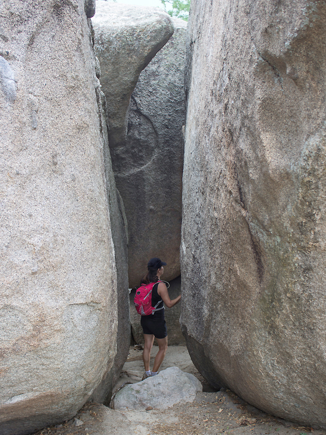 Hiker between immense boulders on the side of the Groom Creek Hiking Trail; Prescott; Arizona; Prescott National Forest; Spruce Mountain; Moderate Hiking Trails; Pet Friendly Hiking Trails. Copyright azutopia.com. No use without permission.