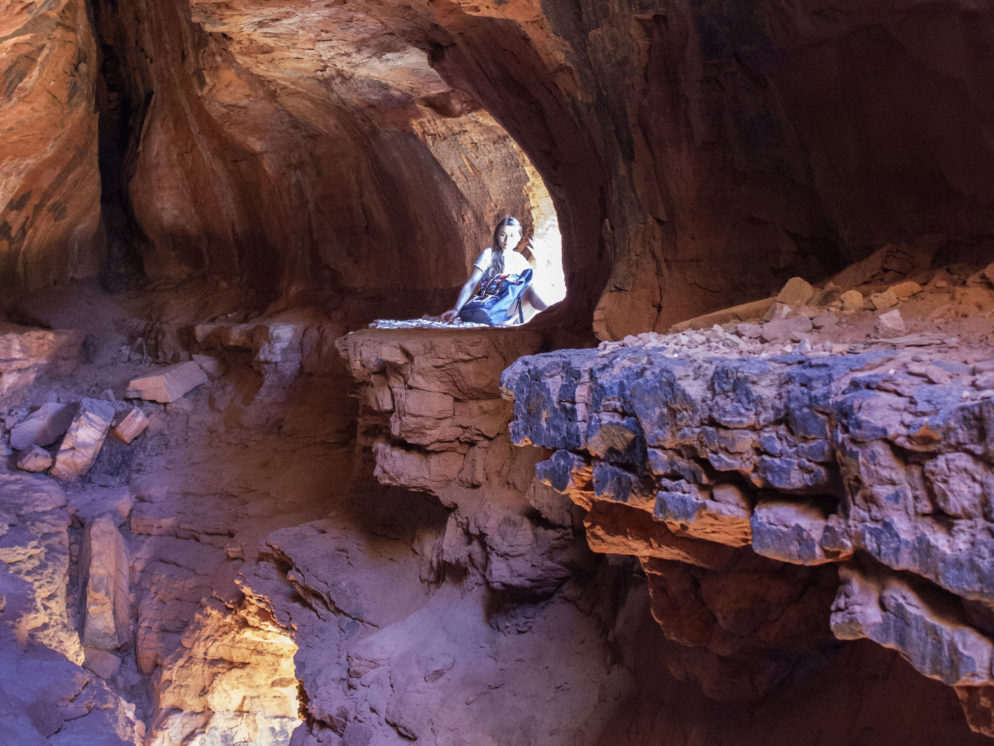 Young Woman with backpack; Hiker; Sitting inside cave; in front of opening; Redrocks; Cliffs; Crevice; Bright light; Soldiers Pass Hiking Trail; Soldiers Pass Caves; Sedona; Arizona; Northern Arizona Hiking Trails; Difficult Hiking Trails; Copyright azutopia.com. No use without permission.